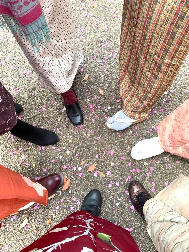 桜の花びらが散る地面と、着物姿の参加者たちの足元